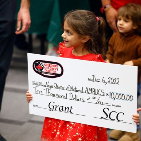 Little girl holding $10k check for Las Vegas Chapter of National AMBUCS
